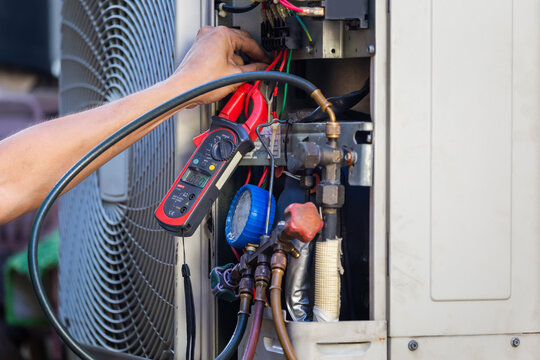 Air conditioning systems - technician performing maintenance with electrical testing equipment